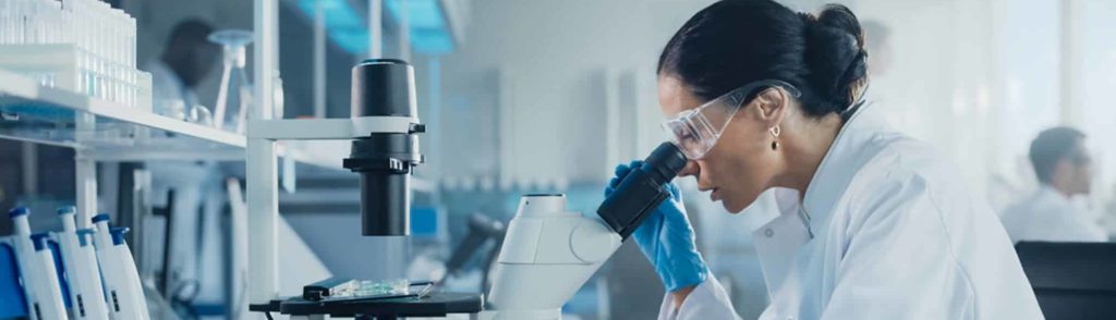 A female scientist looking through a miscroscope in a laboratory.